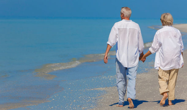 Ein älteres Paar geht händchenhaltend am Strand spazieren